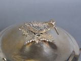 a silver plate with a bird on top of it