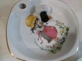 une petite assiette sur laquelle est représentée une fillette tenant un parapluie