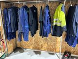 many jackets and pants hanging on a rack in a garage