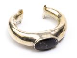 a close up of a gold cuff with a black stone on it