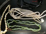 many necklaces and bracelets laid out on a table