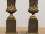 pair of antique bronze vases on pedestals on a table