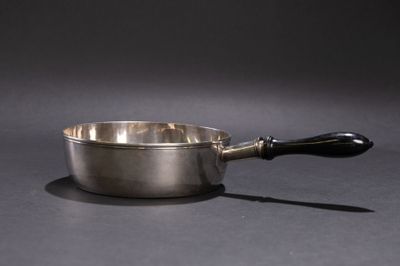 une casserole argentée avec une poignée noire sur un fond gris