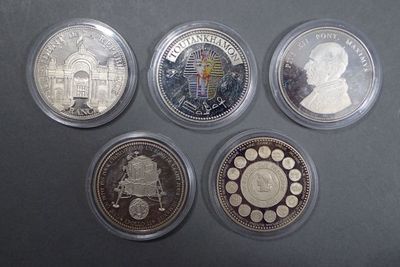 six different coins in a display case on a black surface