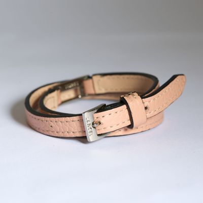 ceinture en cuir rose avec boucle argentée sur fond blanc