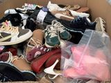 many pairs of shoes in a cardboard box on the floor
