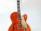 an orange electric guitar sitting on top of a stand on a white surface