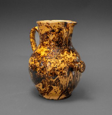un vase marron et noir posé sur une surface grise