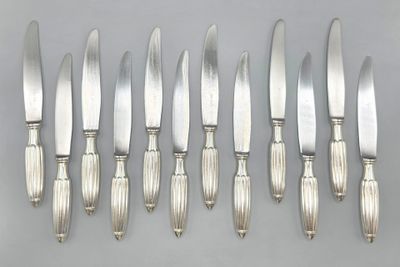 six silverplated knives and six knives on a table