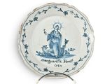 une assiette bleue et blanche sur laquelle est représenté un saint
