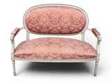 une chaise rose et blanche aux accoudoirs rembourrés et ouvragés