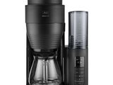 une cafetière noire avec une tasse en verre à côté