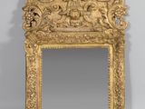 un miroir en or richement décoré, surmonté d'une tête de lion