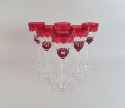 six verres à vin rouges alignés sur une surface blanche