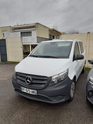une camionnette blanche garée sur un parking à côté d'une voiture noire