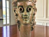 statue représentant la tête d'une femme posée sur une table en bois dans une pièce