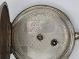 a silver pocket watch that is open on a white surface
