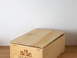 a wooden box on a wooden table with a plant in the background