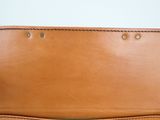 brown leather purse on white surface with white wall in background