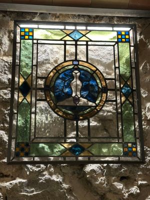 a stained glass window in the corner of a stone wall