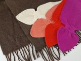 Plusieurs écharpes de différentes couleurs sont disposées sur une surface blanche.