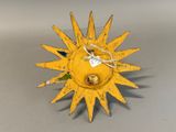 a yellow metal sun with a green leaf on it