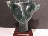 sculpture of a head with horns on a wooden base
