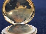 a gold pocket watch sitting on a blue surface