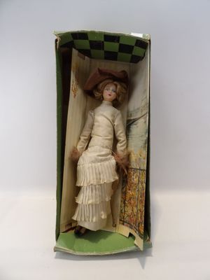 une vieille poupée dans une boîte, avec une robe et un chapeau