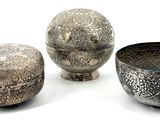 three silver bowls sitting next to each other on a white surface
