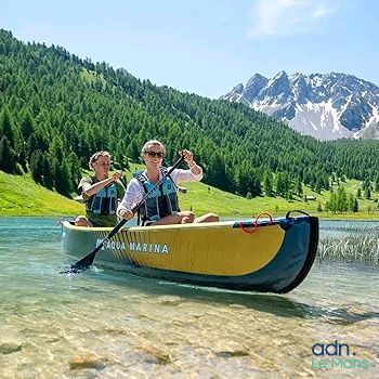 deux personnes dans un canoë sur un lac, avec des montagnes en arrière-plan