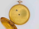 a gold pocket watch that has writing on it