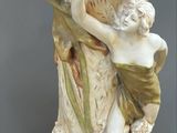 a statue of a woman holding a shell in a vase
