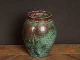 a green and brown vase sitting on a wooden table