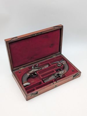an old wooden case with two pistols inside of it