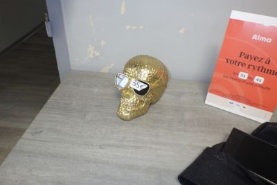 un crâne en or avec des lunettes de soleil posé sur une table à côté d'un livre