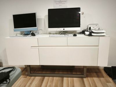 deux écrans d'ordinateur posés sur un meuble blanc dans une pièce