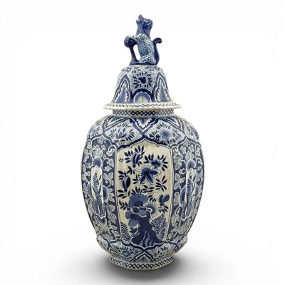 vase bleu et blanc surmonté d'un chat, posé sur un fond blanc