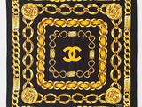 une écharpe noire et dorée ornée de chaînes et du logo Chanel