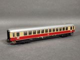 a red and beige train car on a gray surface