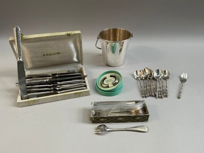 des couverts en argent posés sur une table, accompagnés d'une tasse et d'une cuillère