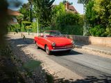 une voiture rouge qui roule dans la rue