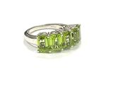 an image of a ring with three green stones on a white surface