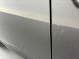 the side of a silver car with a denting dent on it