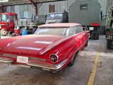 a red car parked in a garage next to a white truck