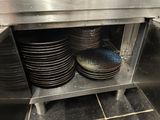 several plates are stacked on a metal shelf in a kitchen