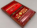 a wooden box with a glass and a gold object in it