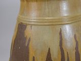 a brown and yellow vase sitting on a white surface