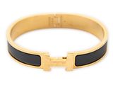 a close up of a gold bracelet with a black enamel band