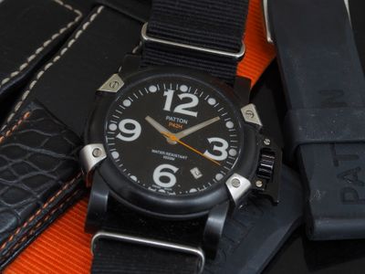 a close up of a watch on a black and orange strap